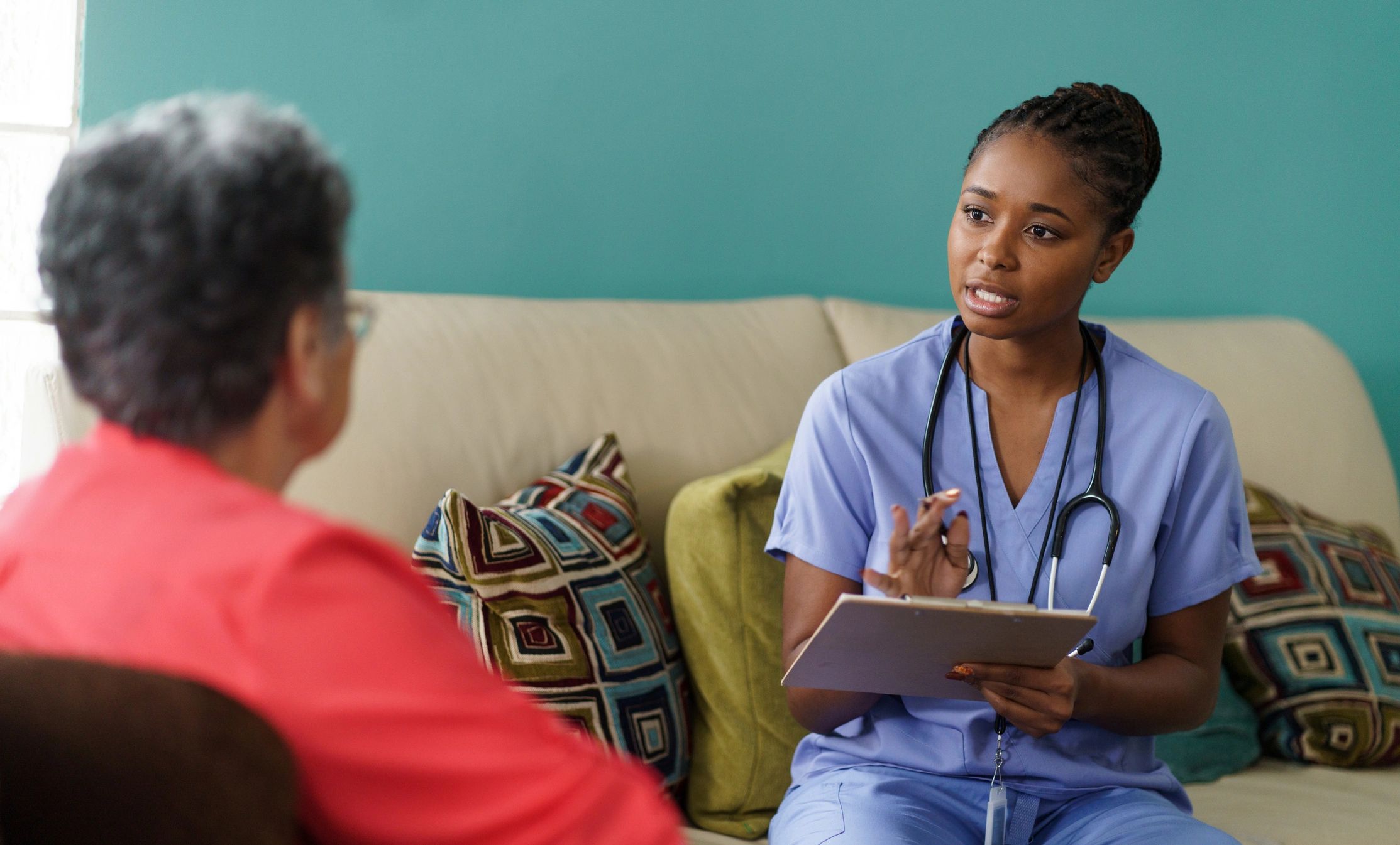 Caregiver visiting and talking with a senior at home