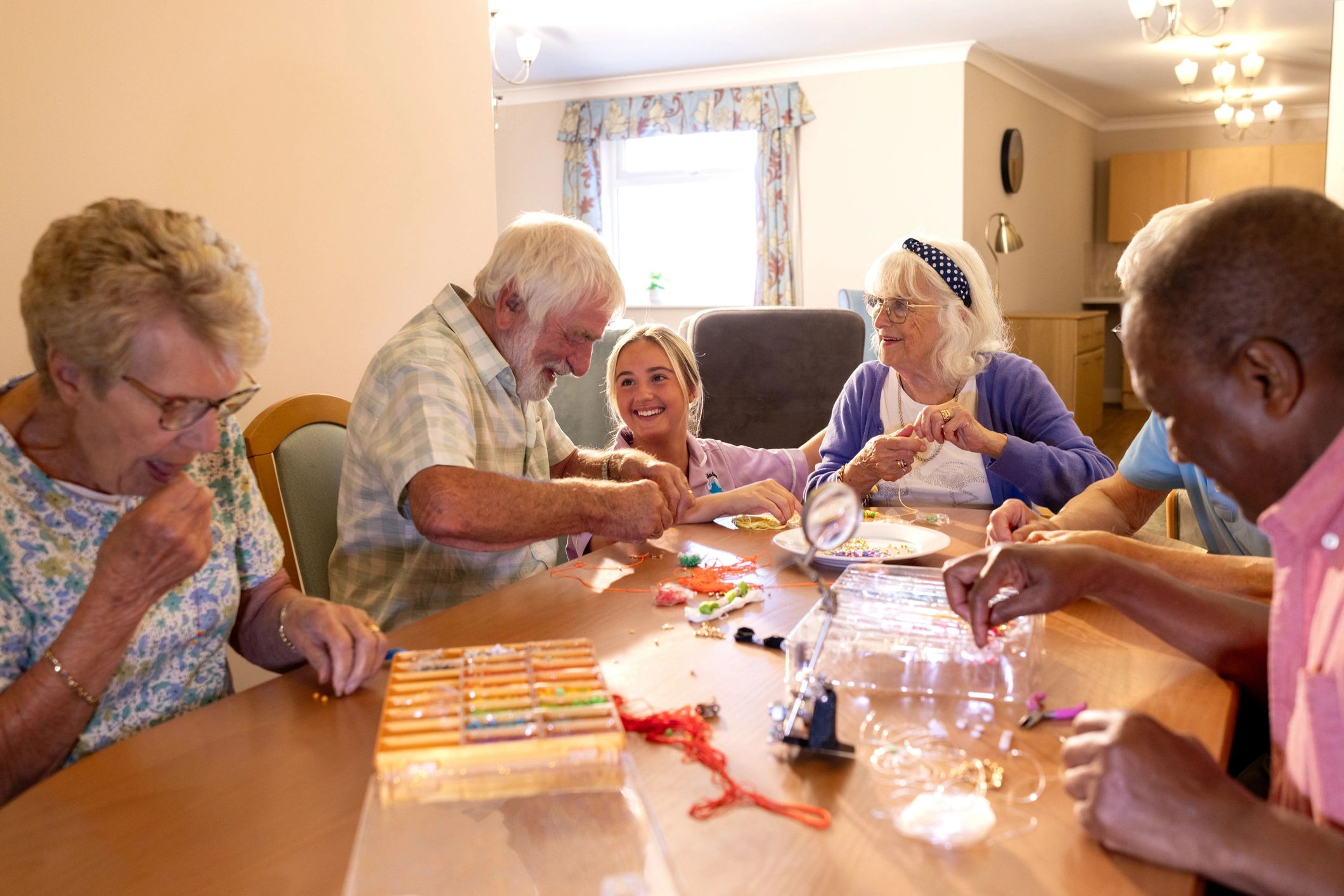 Care worker supporting seniors during a home-style group activity