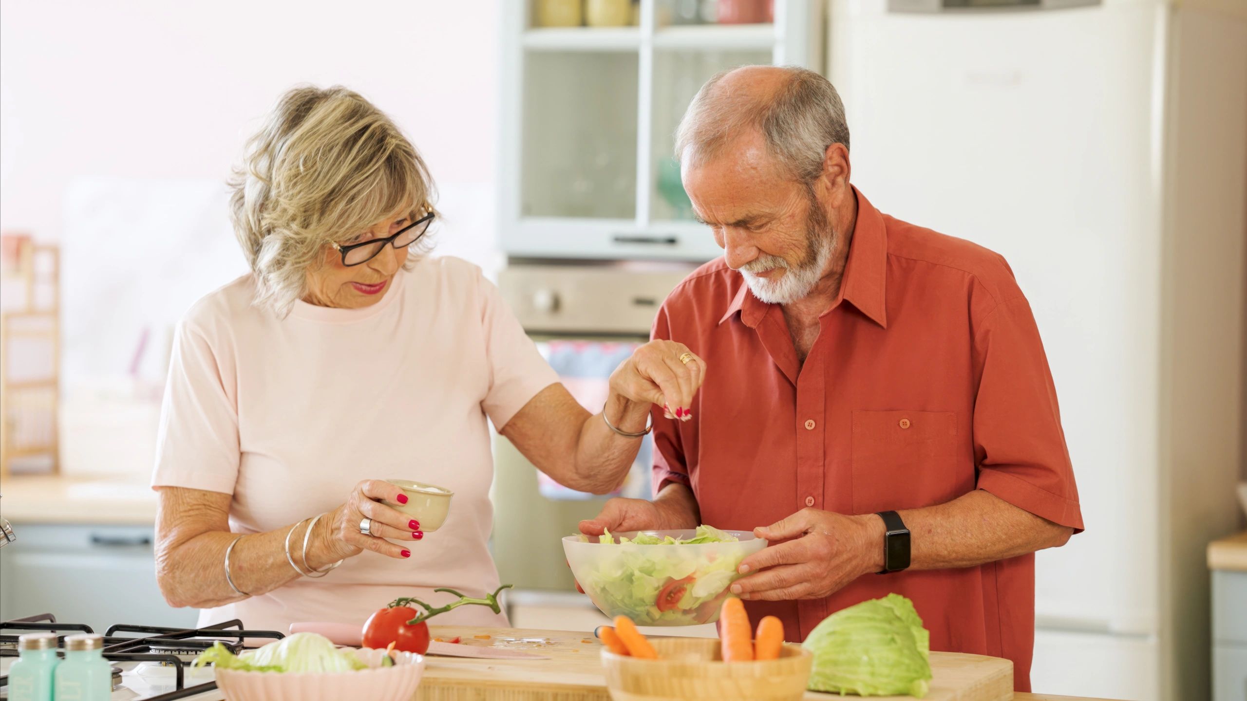 Senior couple preparing healthy salad in kitchen